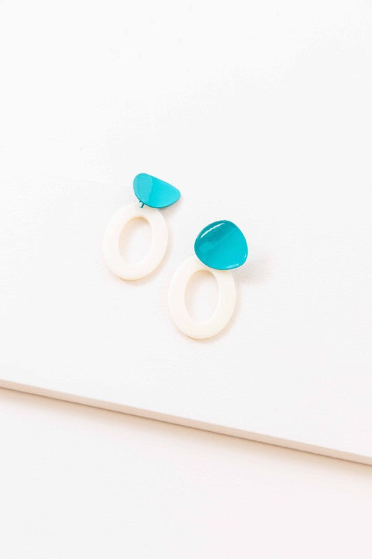 A pair of Bright Color Block Dangle Earrings with teal and white elements on a beige background.