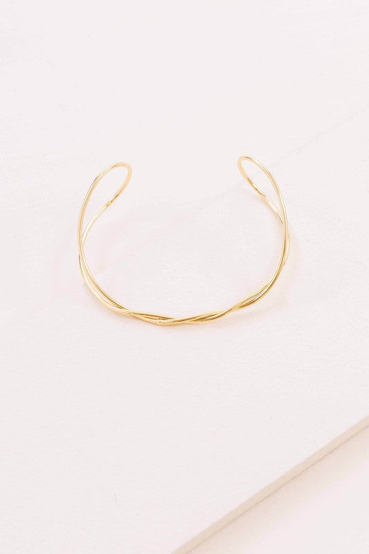A delicate Twister Cuff Bracelet on a pale surface.