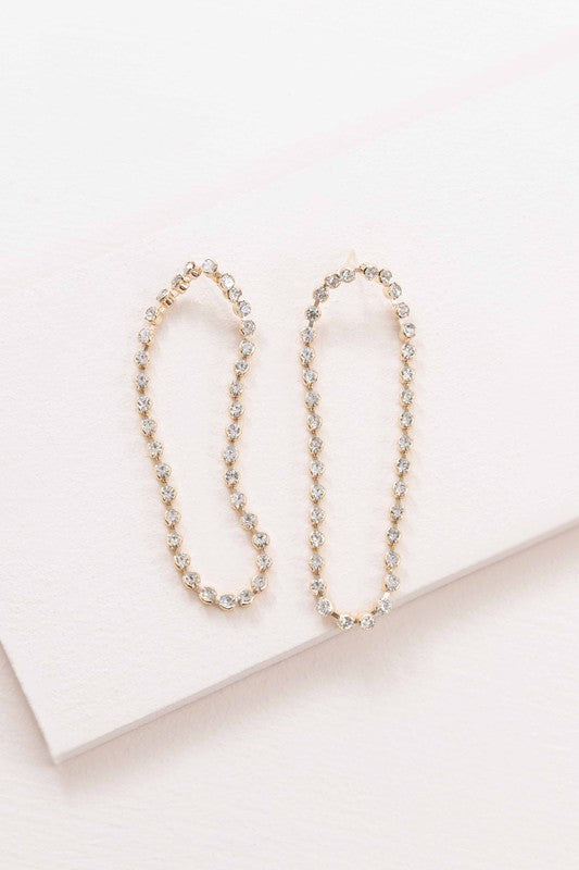 A pair of Can't Get Enough Drop Earrings with embedded crystals on a light background.