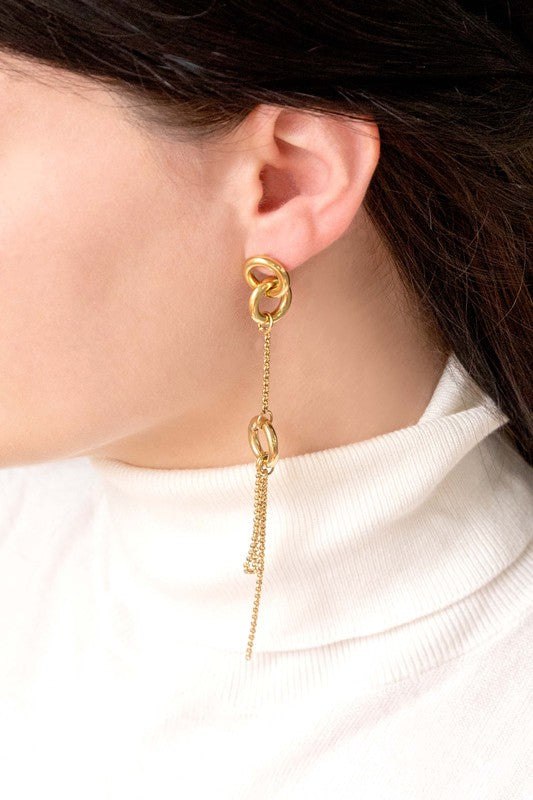 Asymmetrical circle drop earrings with chain and hoop design displayed on a white surface.