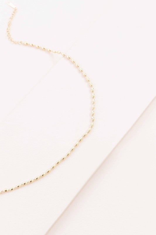 The Gold Beaded Chain Necklace, crafted in 14k gold with intricate details, is elegantly photographed against a white background.