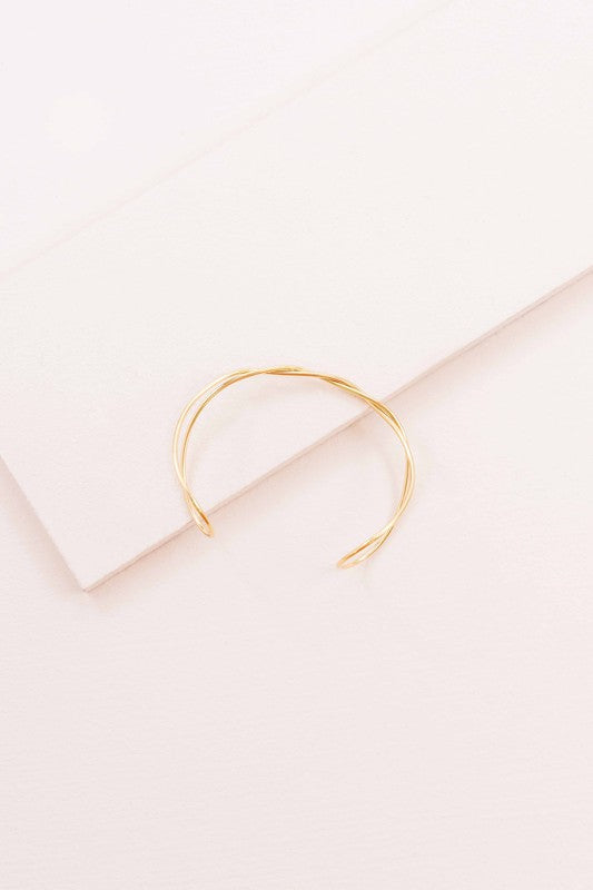 A delicate Twister Cuff Bracelet on a pale surface.