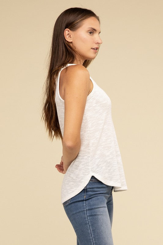 A woman in a stylish and adaptable V Neck Sleeveless Cami Top paired with jeans stands against a beige background. She has long brown hair and maintains a neutral expression.