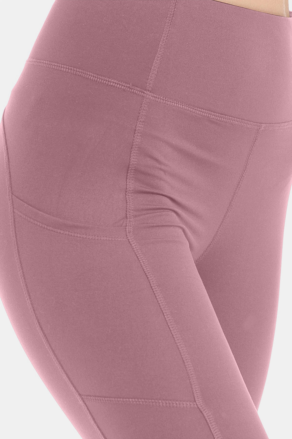 Side view of an individual wearing Leggings Depot Wide Waistband High Waist Leggings in mauve, ideal for high-intensity workouts, with one hand in the pocket and white sneakers, standing against a plain white background.