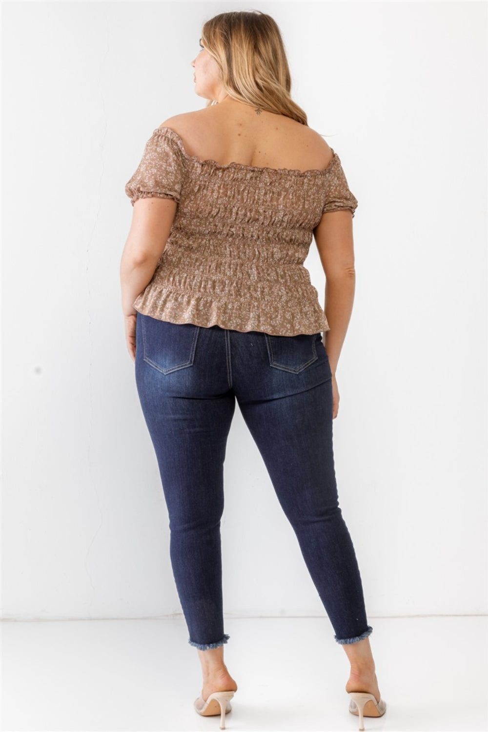 Wearing the Zenobia Plus Size Frill Ruched Off-Shoulder Short Sleeve Blouse and ripped jeans, a person with long hair poses against a plain white background.