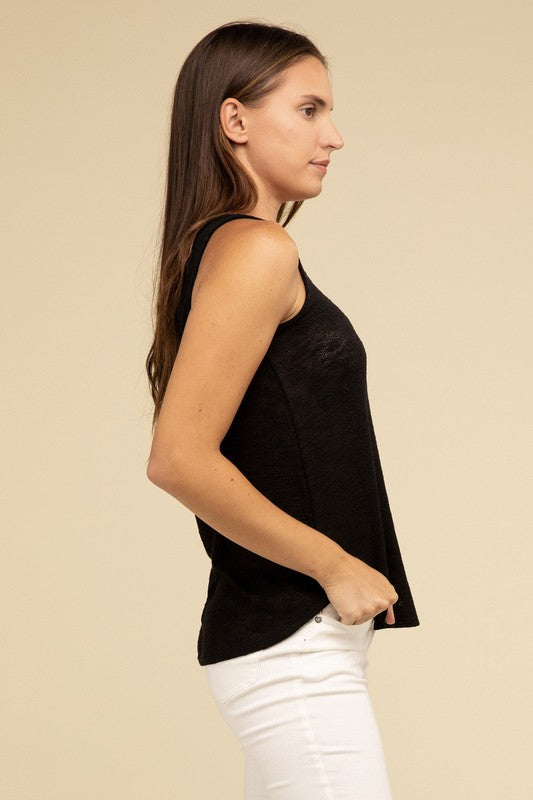 A woman in a stylish and adaptable V Neck Sleeveless Cami Top paired with jeans stands against a beige background. She has long brown hair and maintains a neutral expression.