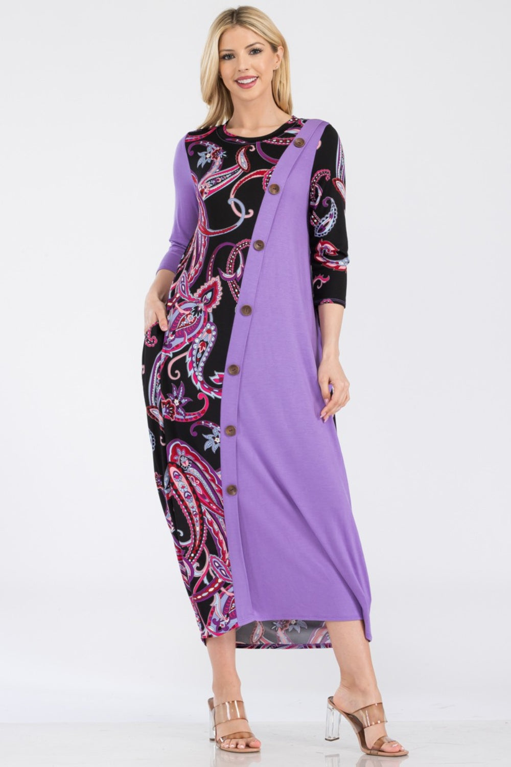 A woman wearing the Celeste Full Size Paisley Contrast Midi Dress with pockets, showcasing a versatile purple and black paisley print, button front detail, and long sleeves.