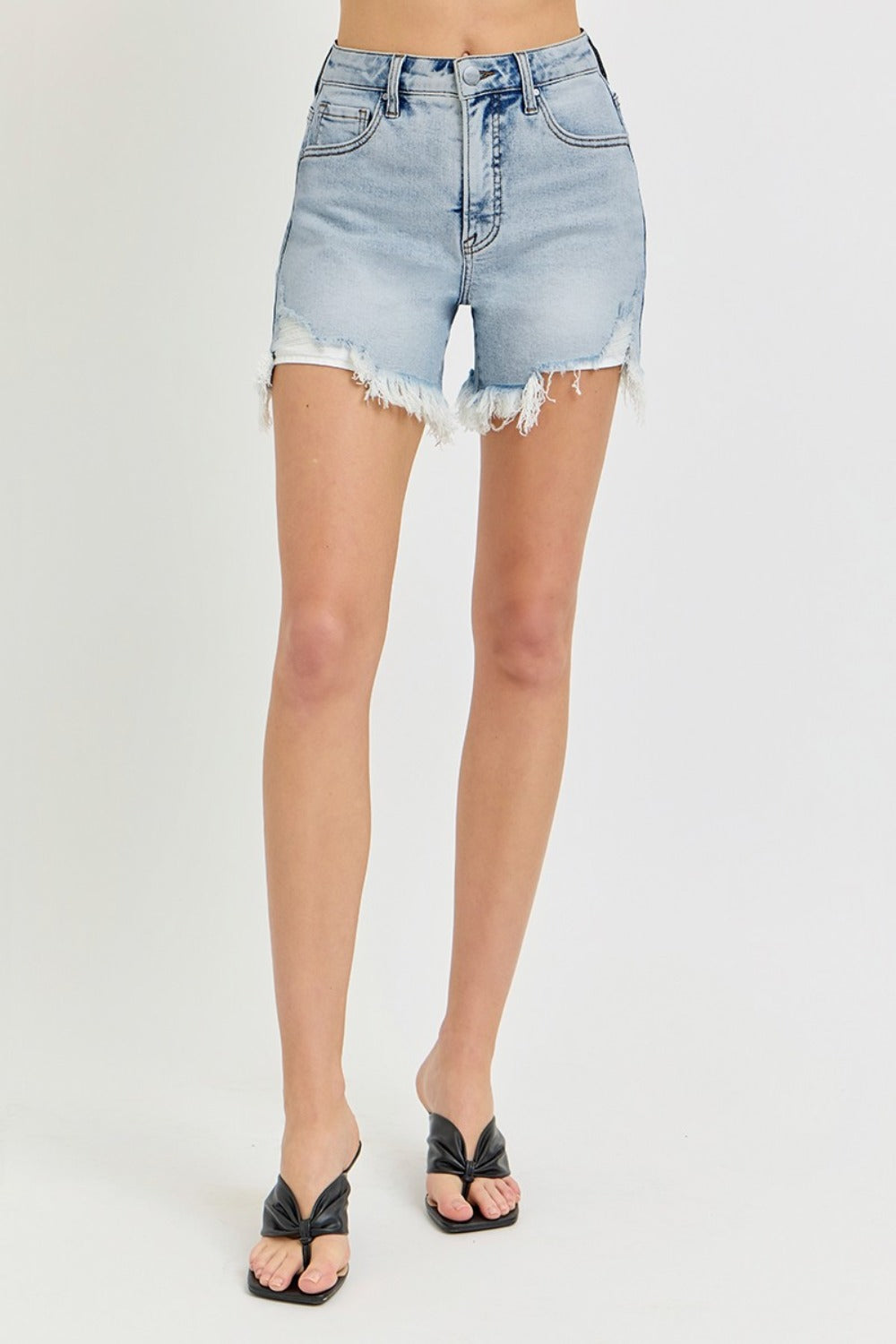 A person wearing the RISEN High Rise Side Step Hem Denim Shorts featuring light-wash, frayed hems, front pockets, and a versatile design.