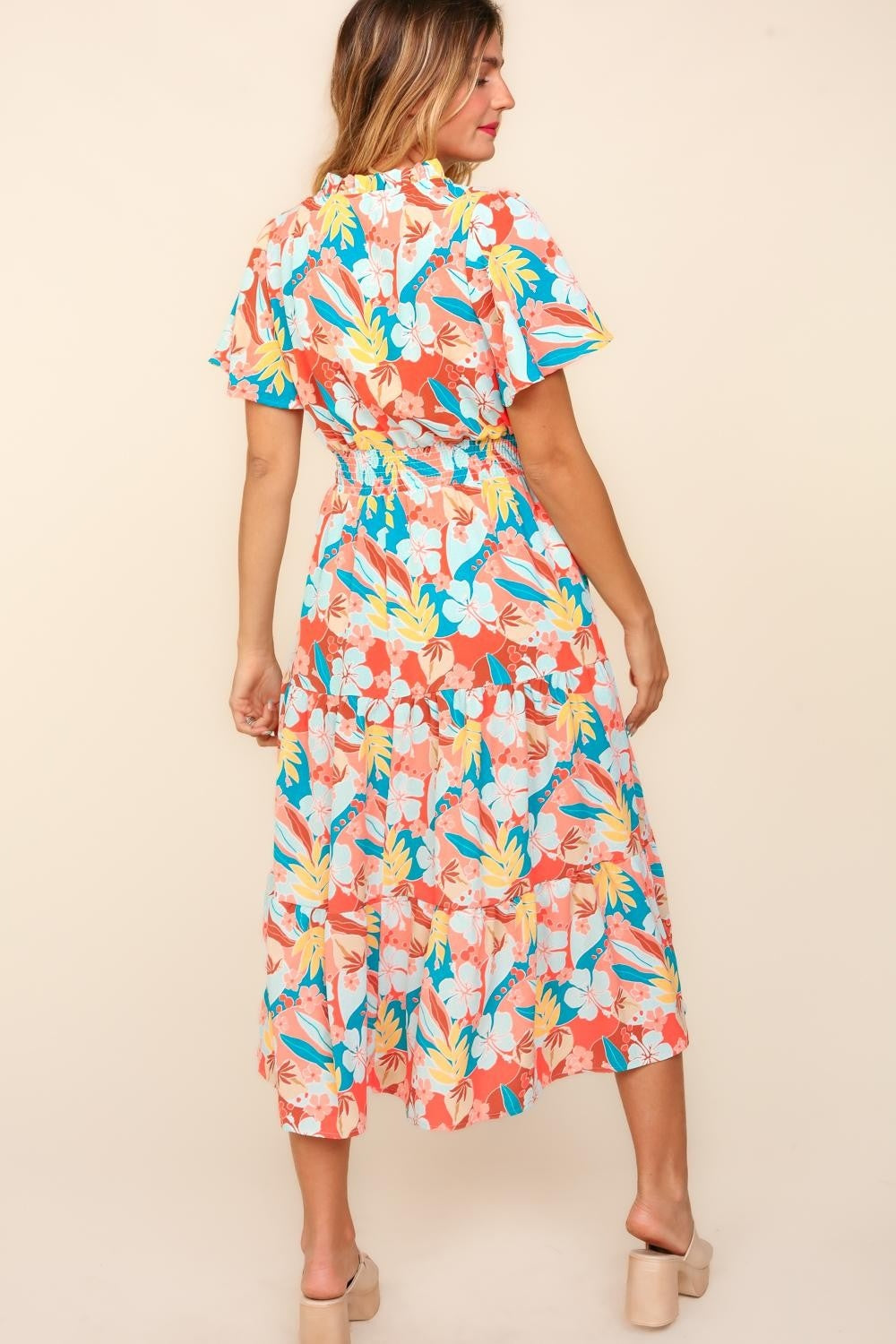 A person wearing the Haptics Full Size Tropical Floral Tiered Dress with Side Pockets and beige platform sandals stands against a plain background.