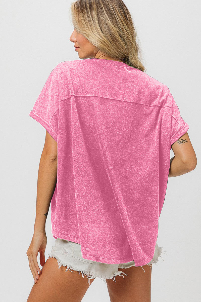 A person wearing a stunning pink BiBi Sequin Baseball Short Sleeve T-Shirt, combined with versatile styling options such as crisp white shorts, standing against a plain background.