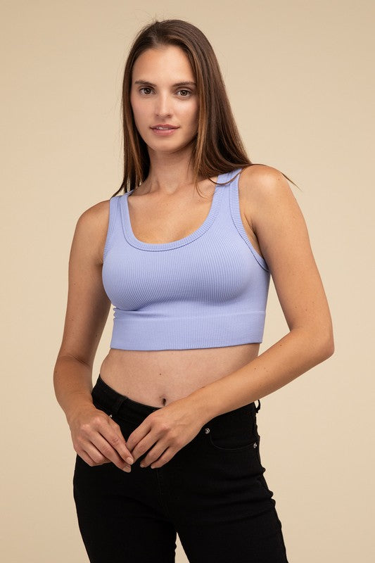 A person with long brown hair wearing the Ribbed Seamless Crop Top in light blue and black pants stands against a beige background, showcasing a perfect summer essential.