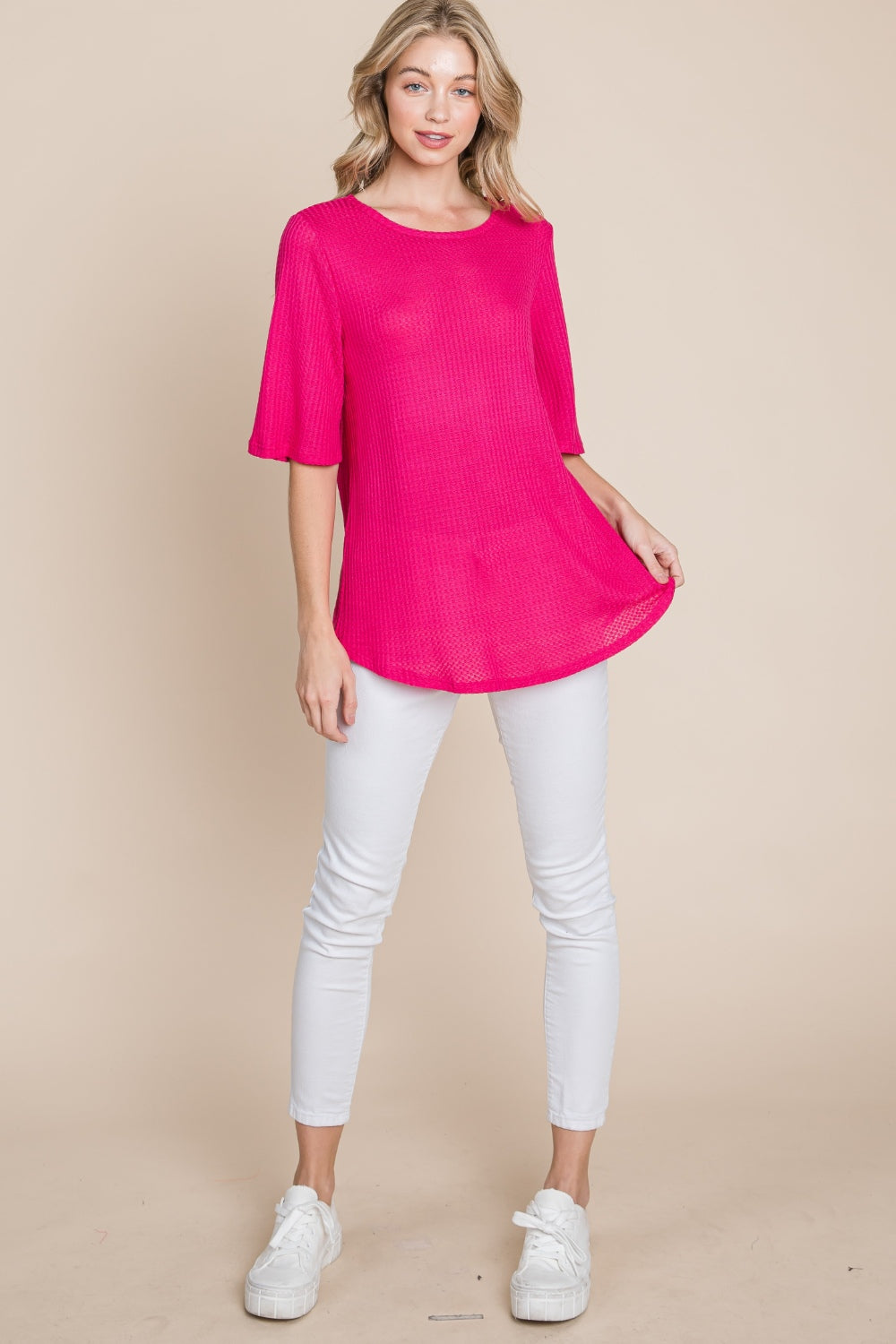 A person is wearing a BOMBOM Round Neck Waffle Knit T-Shirt in bright pink with white pants, standing against a beige background.