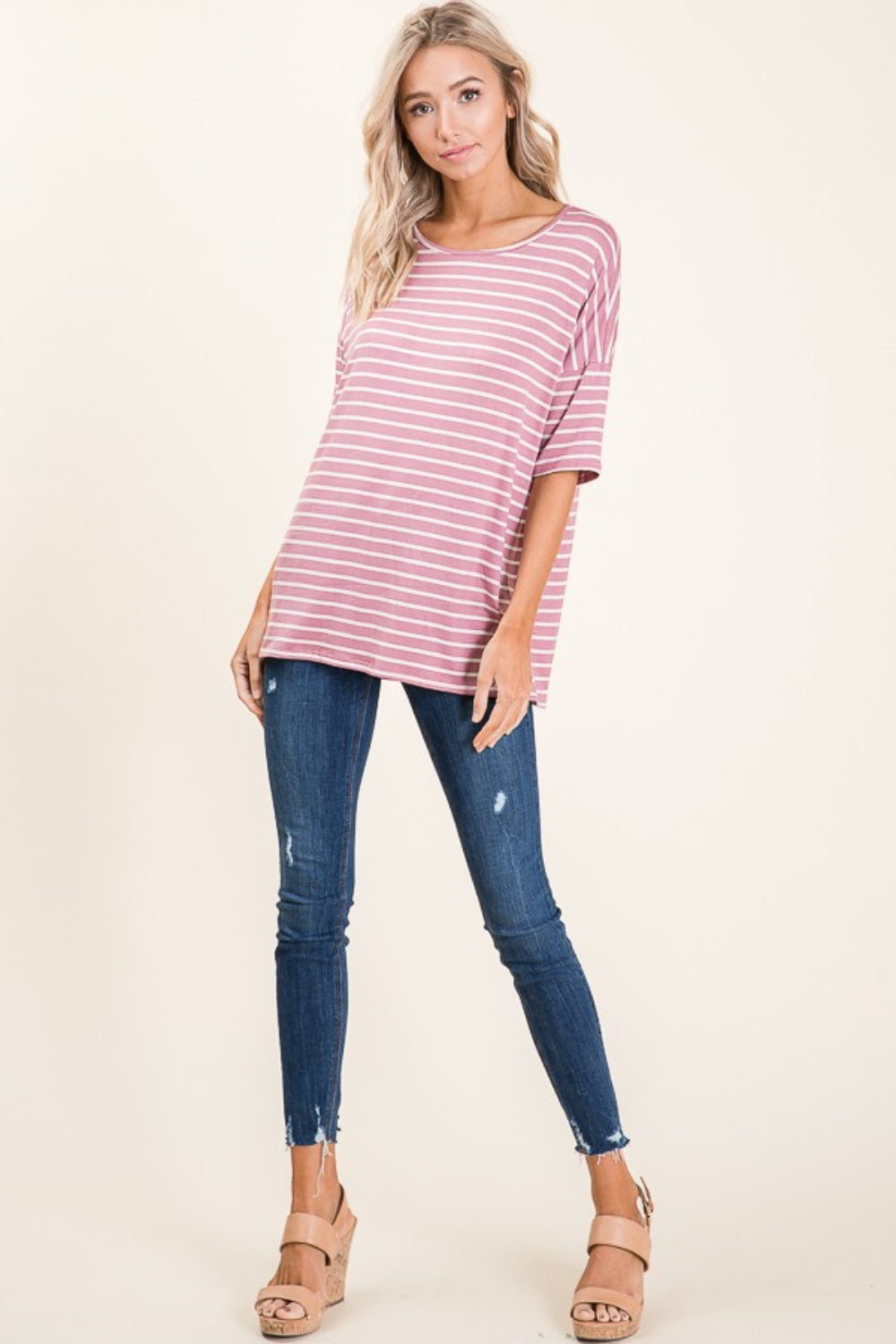 A person wearing a BOMBOM Striped Round Neck Half Sleeve T-Shirt in pink and white paired with blue jeans stands against a neutral background.