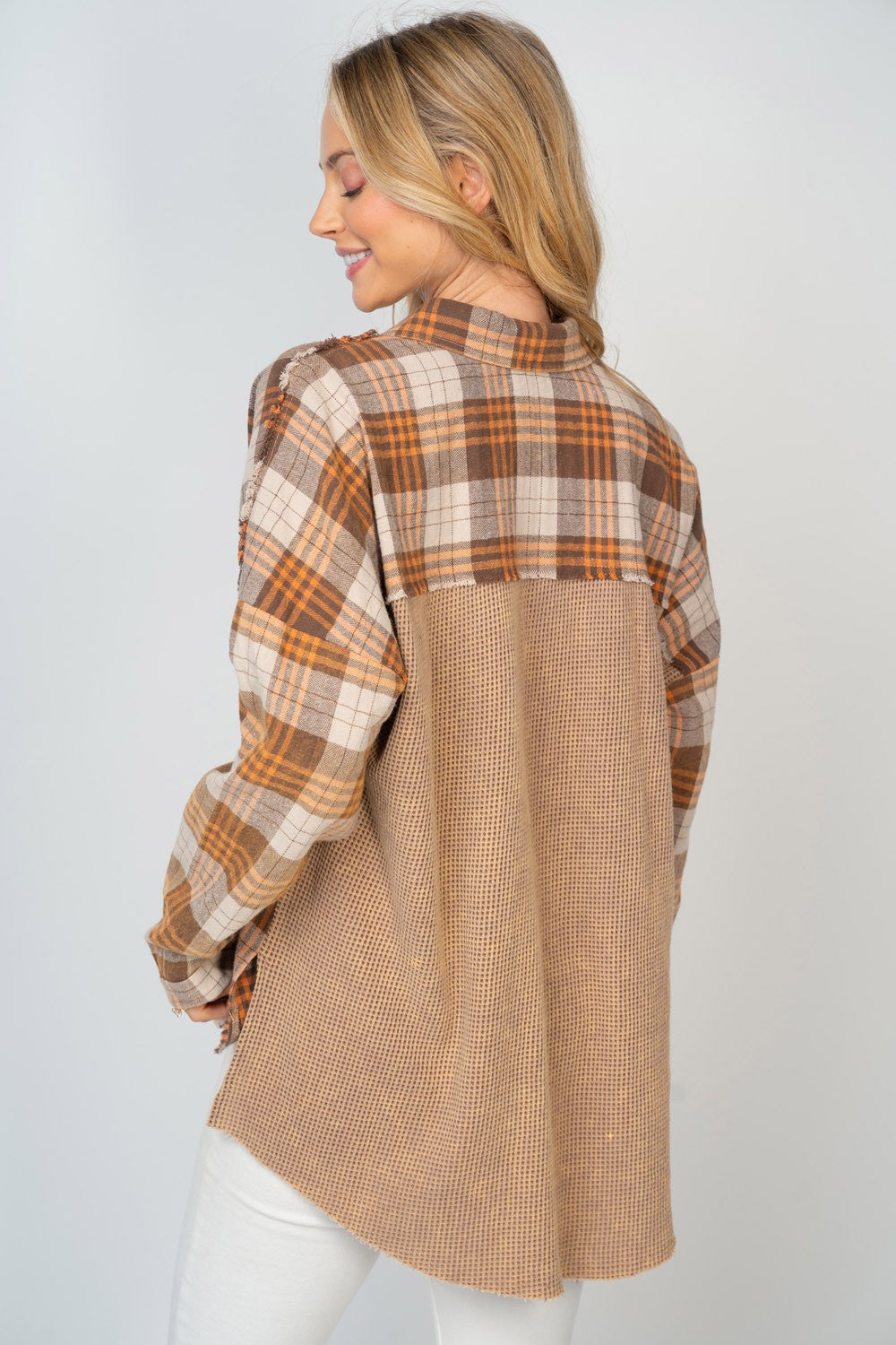 A person with long, blonde hair smiles while wearing the White Birch Full Size Contrast Plaid Button Down Shirt in beige, brown, and white hues, paired with white pants.