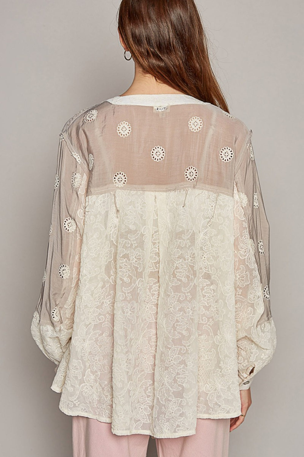 A person is wearing the POL Eyelet Button-Up Shirt with floral patterns over a lace top and pink pants, standing in front of a neutral background. This versatile wardrobe staple perfectly combines elegance and style.