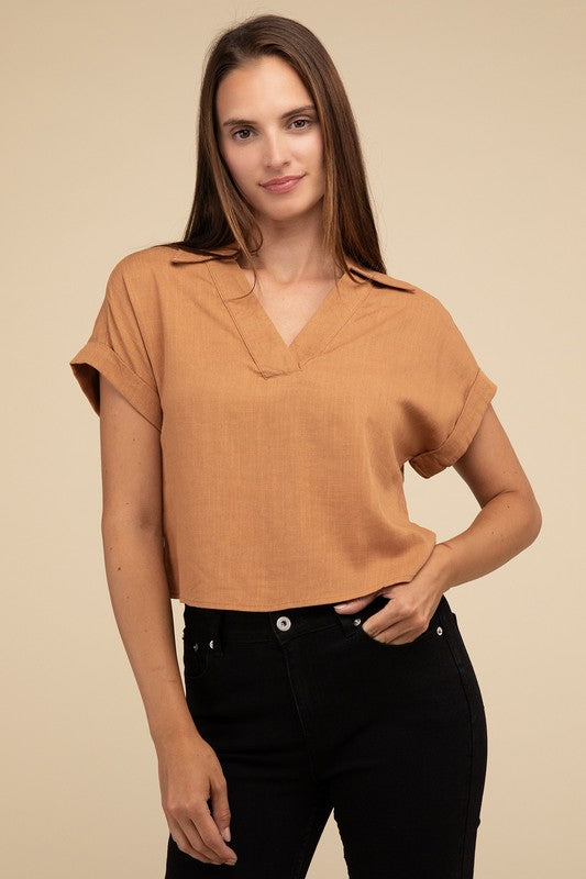 A woman with long hair is wearing the Always a Delight Short Sleeve Linen Top in brown and black pants, standing against a beige background.