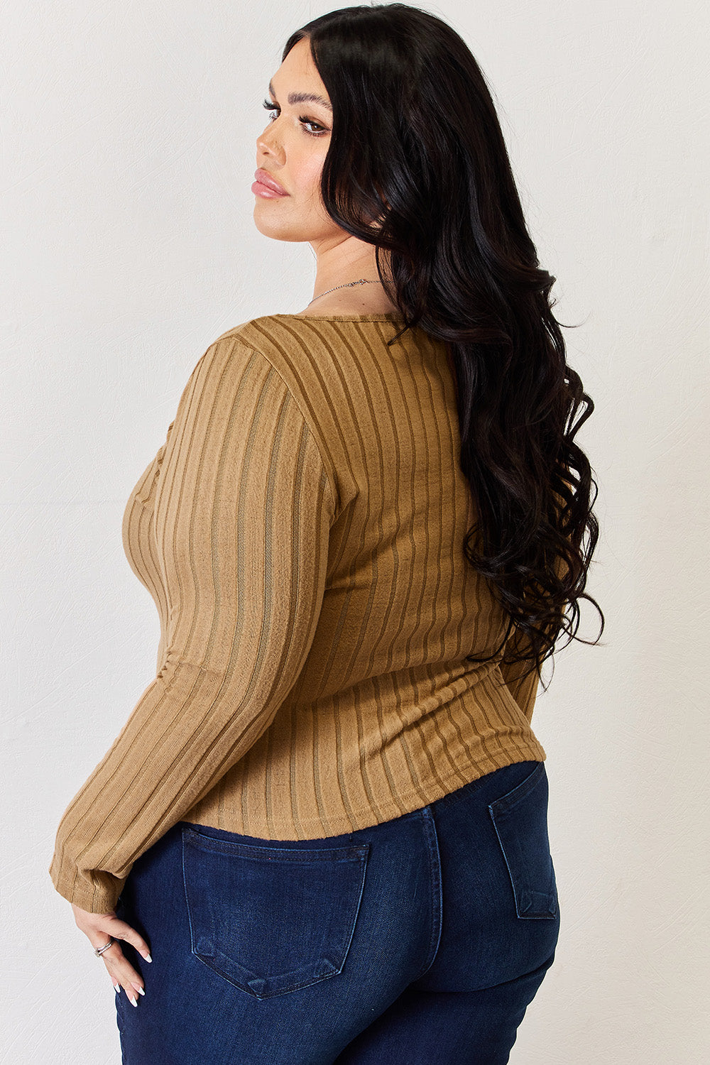 A person is standing and smiling, wearing the Basic Bae Full Size Ribbed Long Sleeve T-Shirt in light brown along with jeans. The basic style is perfect for any casual outing.