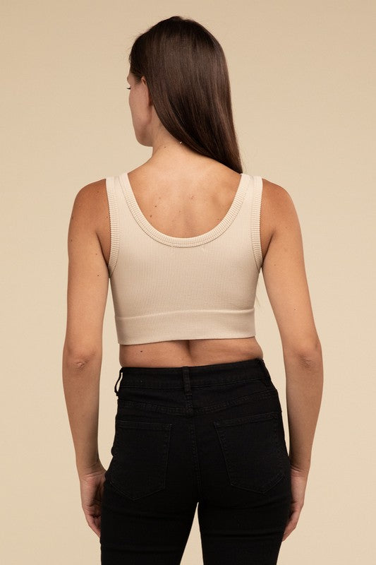 A person with long brown hair wearing the Ribbed Seamless Crop Top in light blue and black pants stands against a beige background, showcasing a perfect summer essential.