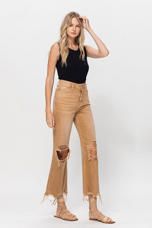 A person wearing 90's Vintage Crop Flare in a brown color and strappy sandals, standing against a plain background.