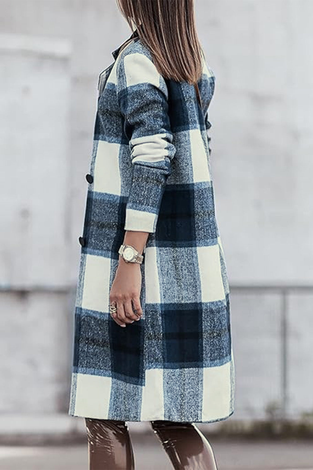 A woman stands on a sidewalk wearing the Double Take Full Size Plaid Button Up Lapel Collar Coat in pink and white over a white top and blue jeans, with her right hand lightly touching her hair. The polyester fabric of the coat makes it durable and perfect for an easy machine wash cold.