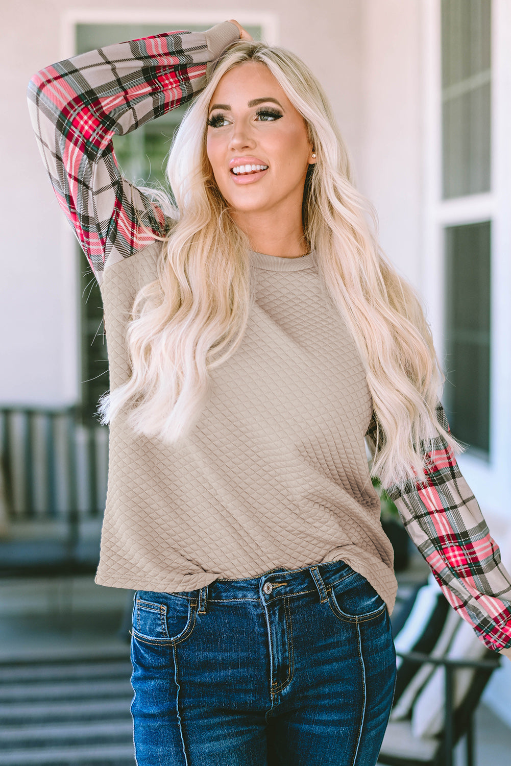 A person with long blonde hair stands with their back to the camera, wearing an Apricot Plaid Raglan Sleeve Sweatshirt and blue jeans.