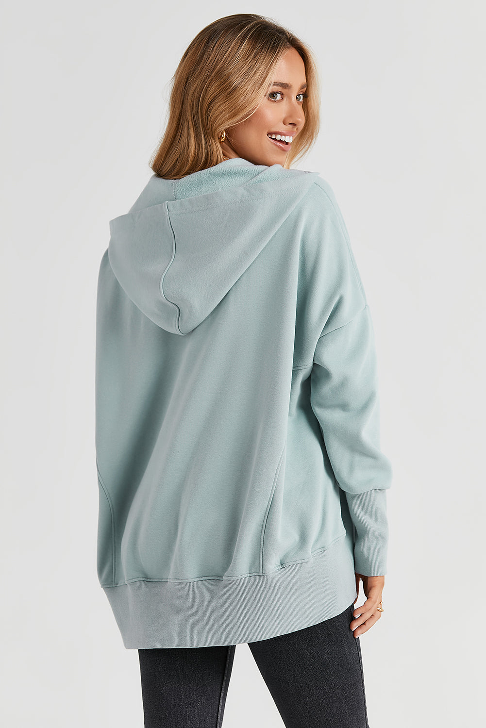 A person with long hair is smiling and looking over their shoulder while wearing a Gray Batwing Sleeve Pocketed Henley Hoodie.