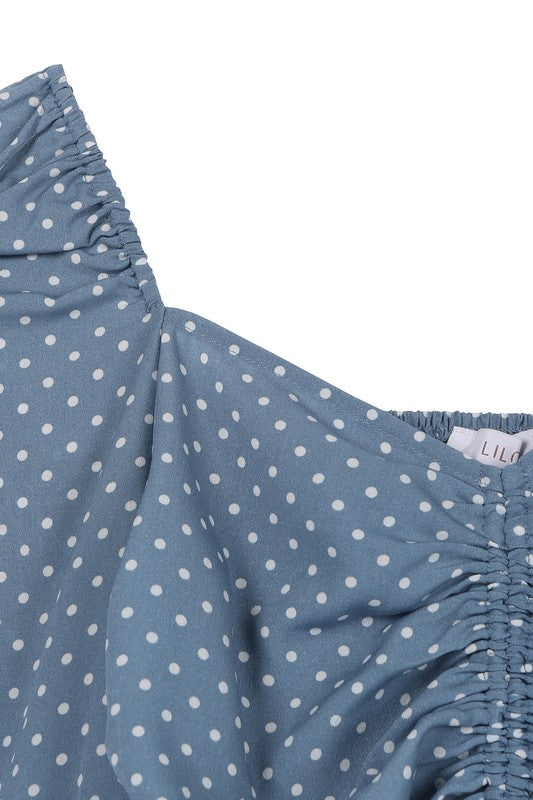 A person wearing the Ruched polka dot crop top with puff sleeves and white shorts poses against a light background.