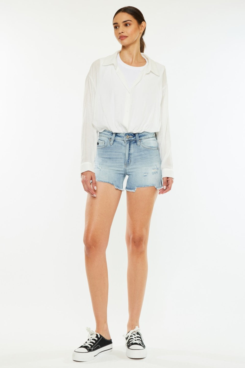 A person wearing a white shirt and the chic Kancan High Rise Side Slit Denim Shorts stands against a plain background, showcasing a perfect addition to any summer wardrobe.