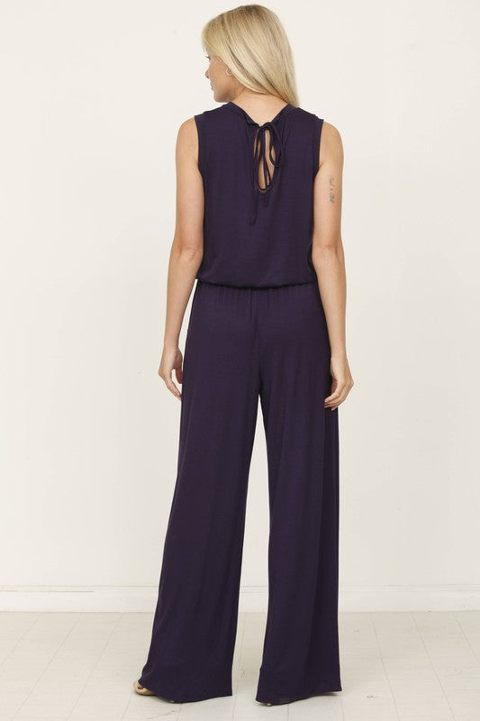 A person poses indoors against a white background, wearing the Plus Solid Drawstring Pocket Jumpsuit in a sleek olive green, crafted from soft rayon with a stylish drawstring detail.