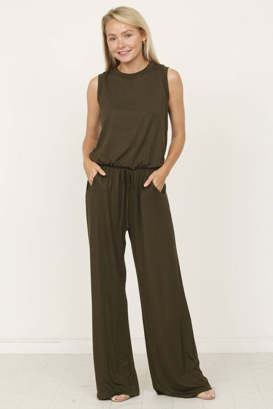 A person poses indoors against a white background, wearing the Plus Solid Drawstring Pocket Jumpsuit in a sleek olive green, crafted from soft rayon with a stylish drawstring detail.