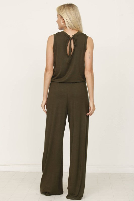 A person poses indoors against a white background, wearing the Plus Solid Drawstring Pocket Jumpsuit in a sleek olive green, crafted from soft rayon with a stylish drawstring detail.