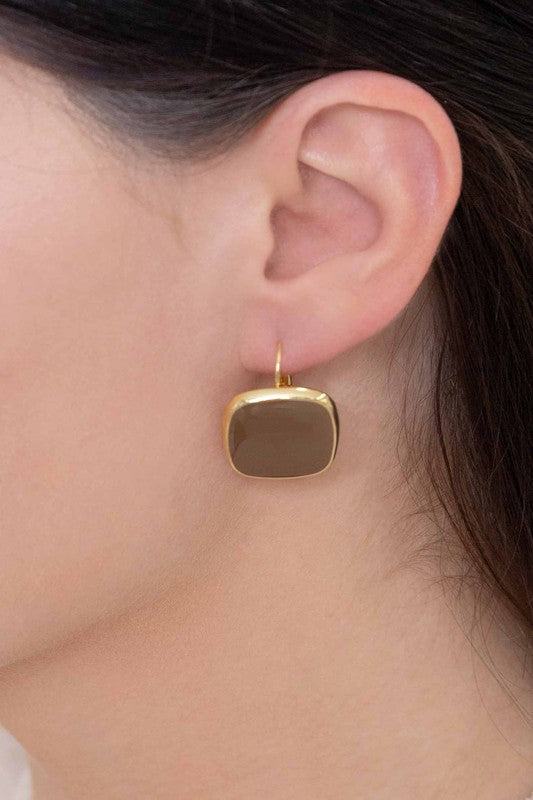 The On the Go Hook Earrings 14K, a pair of square, yellow earrings with 14K gold plate trim, rest on a white surface, bringing a hint of casual style with their elegant yet understated design.