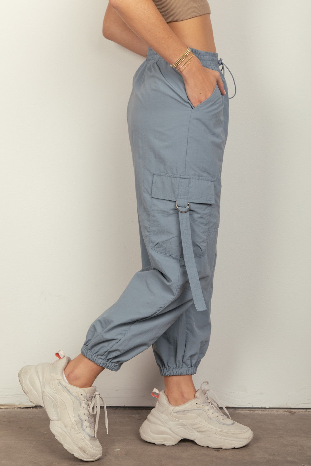 Person wearing VERY J Elastic Waist Woven Cargo Pants in light blue with hands in pockets, paired with white sneakers, standing against a plain background.