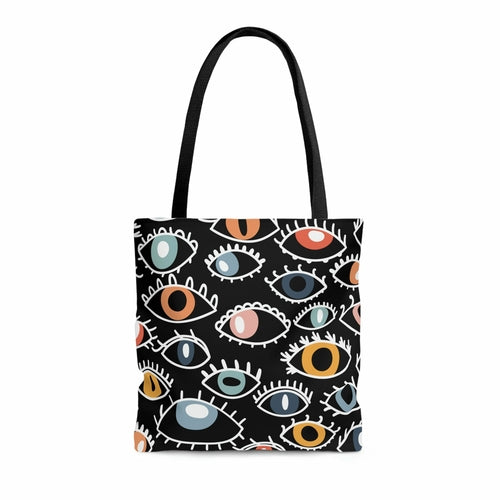 A shopping tote bag featuring a pattern of stylized Egyptian eyes in various colors and designs on a black background, complete with black cotton handles.