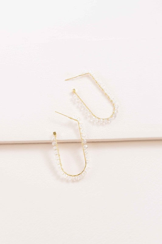 Beaded Racetrack Hoop Earrings featuring gold wire and accented with emerald green beads, displayed on a white surface.