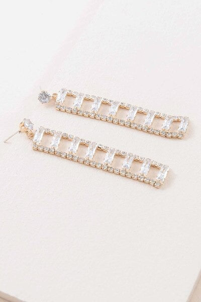 A Dozen Diamonds Dangle Earrings on a pale pink background.