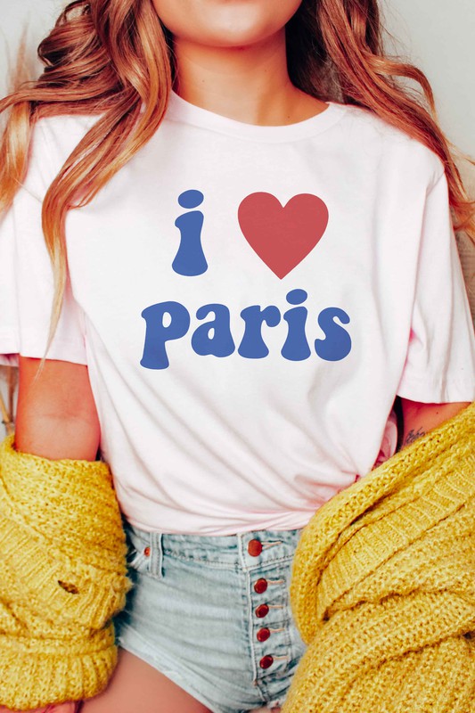 Person wearing a unisex "I LOVE PARIS" graphic tee made from 100% Airlume combed and ringspun cotton, high-waisted denim shorts, and a yellow knit sweater draped over their arms.