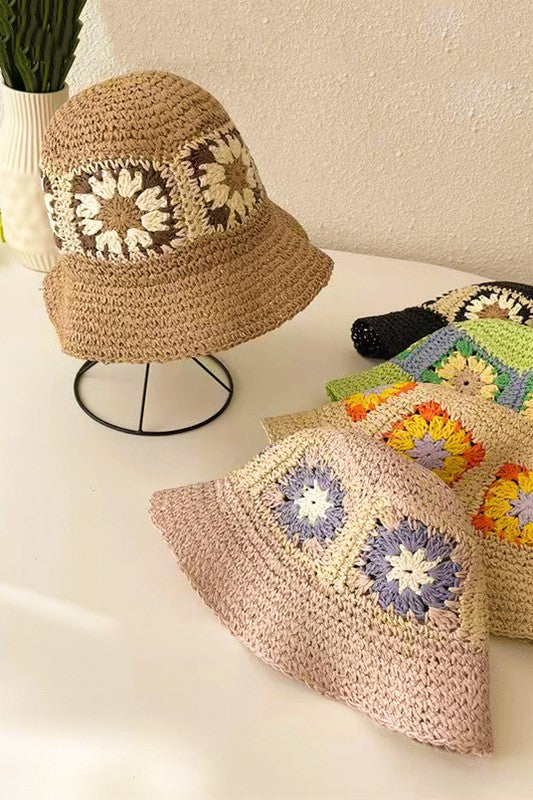 A set of four packable crochet granny square bucket hats in beige, black, and charming patterns featuring yellow flower designs, all lovingly hand-crocheted to perfection.