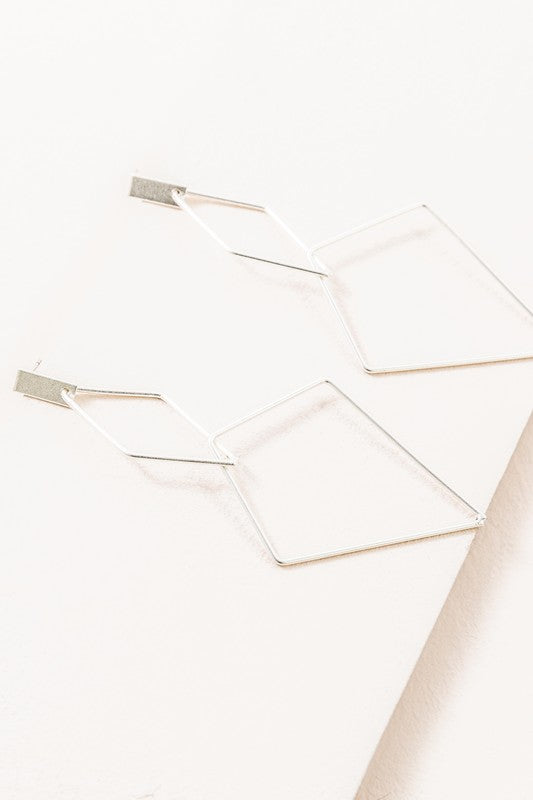 The Shape Of You Drop Earrings, featuring geometric and angular abstract designs crafted in sterling silver, are displayed against a plain white background.