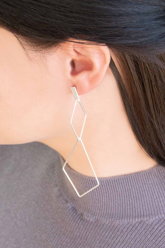 The Shape Of You Drop Earrings, featuring geometric and angular abstract designs crafted in sterling silver, are displayed against a plain white background.