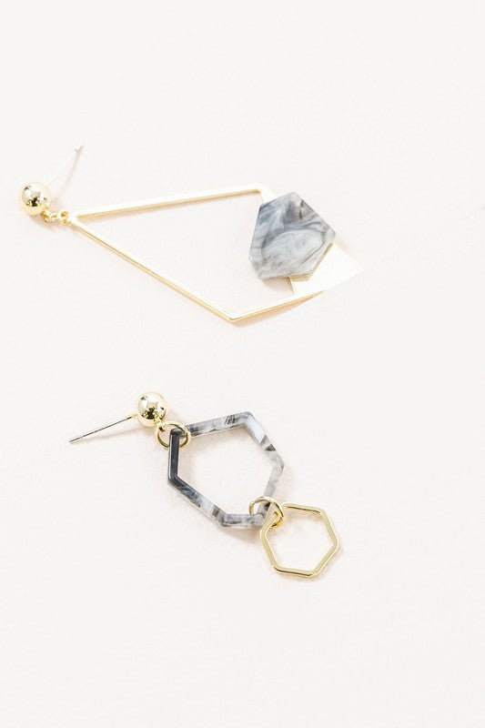 Introducing the Marble Drop Earrings, which showcase an asymmetric geometric design with mismatched elements: one earring features a large stone and triangle with 14k gold-plated accents, while the other earring includes a hexagon and small bead.