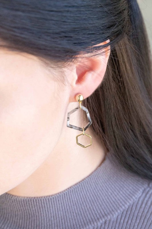 Introducing the Marble Drop Earrings, which showcase an asymmetric geometric design with mismatched elements: one earring features a large stone and triangle with 14k gold-plated accents, while the other earring includes a hexagon and small bead.