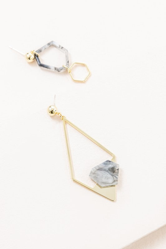 Introducing the Marble Drop Earrings, which showcase an asymmetric geometric design with mismatched elements: one earring features a large stone and triangle with 14k gold-plated accents, while the other earring includes a hexagon and small bead.