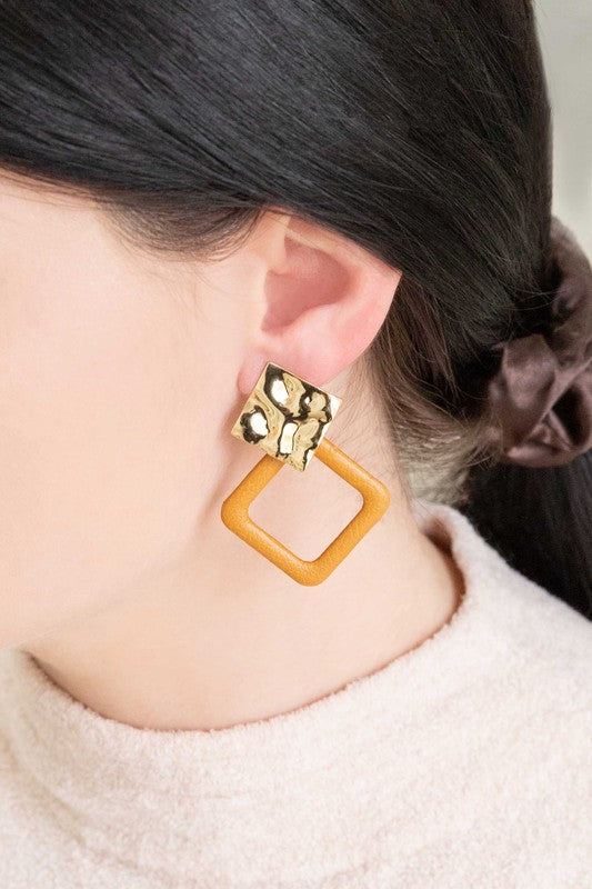 The Leatherette and Metal Drop Earrings showcase a bold design with two hammered 14k gold-plated brass squares linked to orange leather-like square loops.