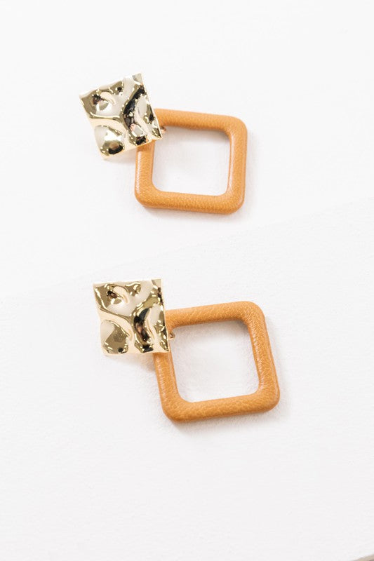 The Leatherette and Metal Drop Earrings showcase a bold design with two hammered 14k gold-plated brass squares linked to orange leather-like square loops.