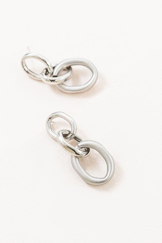 The Let's Link Up Earrings, featuring a pair of gun-metal chained drop design with sterling silver posts, are elegantly showcased on a light background.