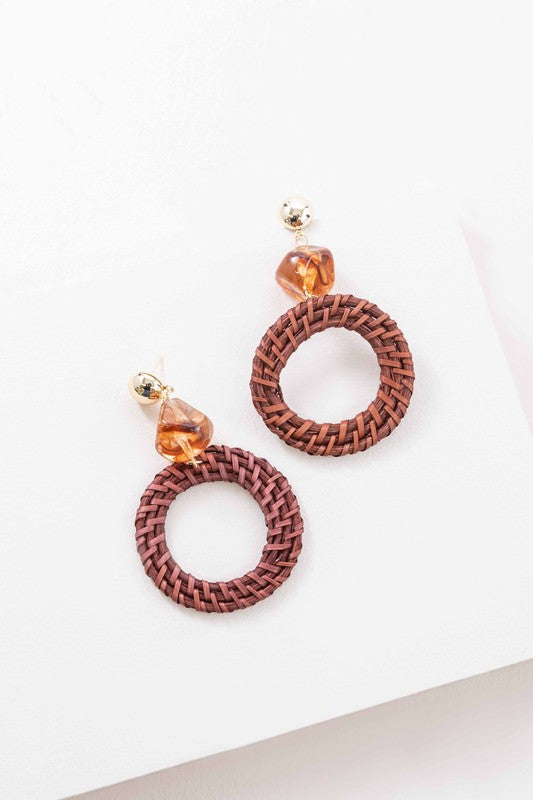 The Wicker and Amber Drop Earrings are beautifully designed with intricately woven wicker combined with amber beads and gold accents, all set against a white backdrop to add an elegant touch.