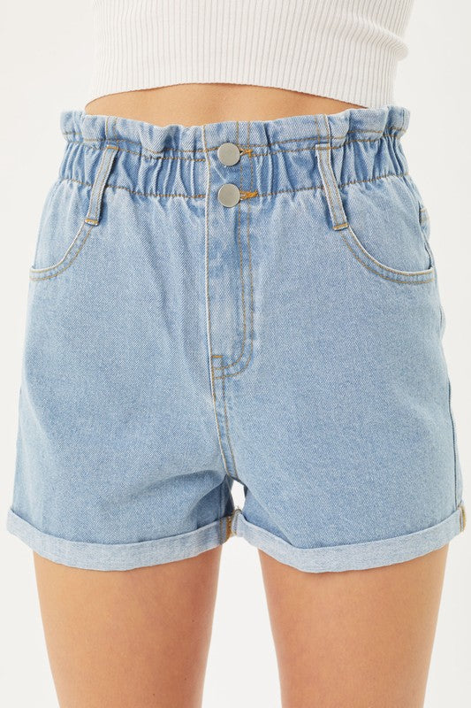 A person wearing light blue Double Buttoned Waistband Denim Shorts with rolled hems, paired with a white ribbed top.