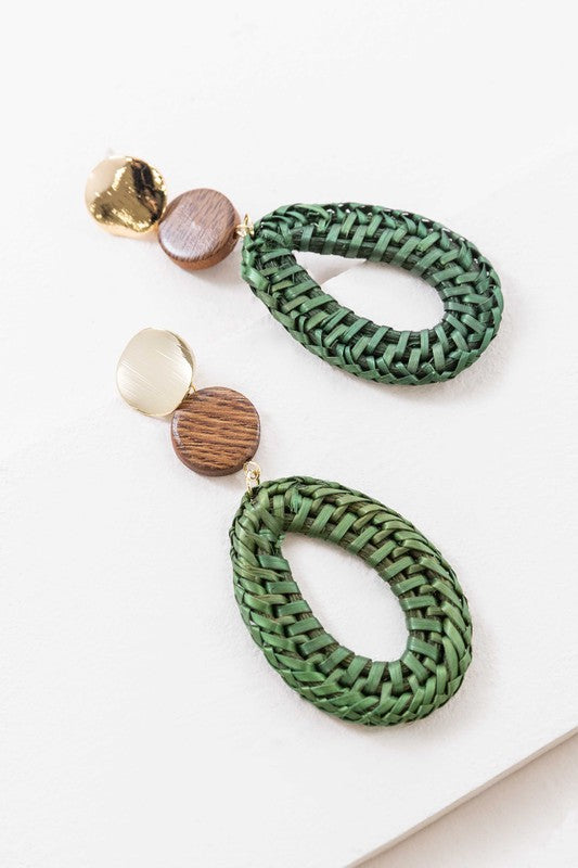 The Oval Wicker Drop Earrings exude tropical vibes with their green wicker design, complemented by round wooden and gold-toned accents, and feature a sterling silver post set against a white background.