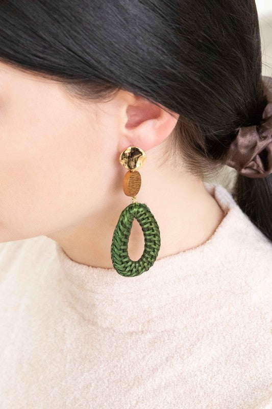 The Oval Wicker Drop Earrings exude tropical vibes with their green wicker design, complemented by round wooden and gold-toned accents, and feature a sterling silver post set against a white background.